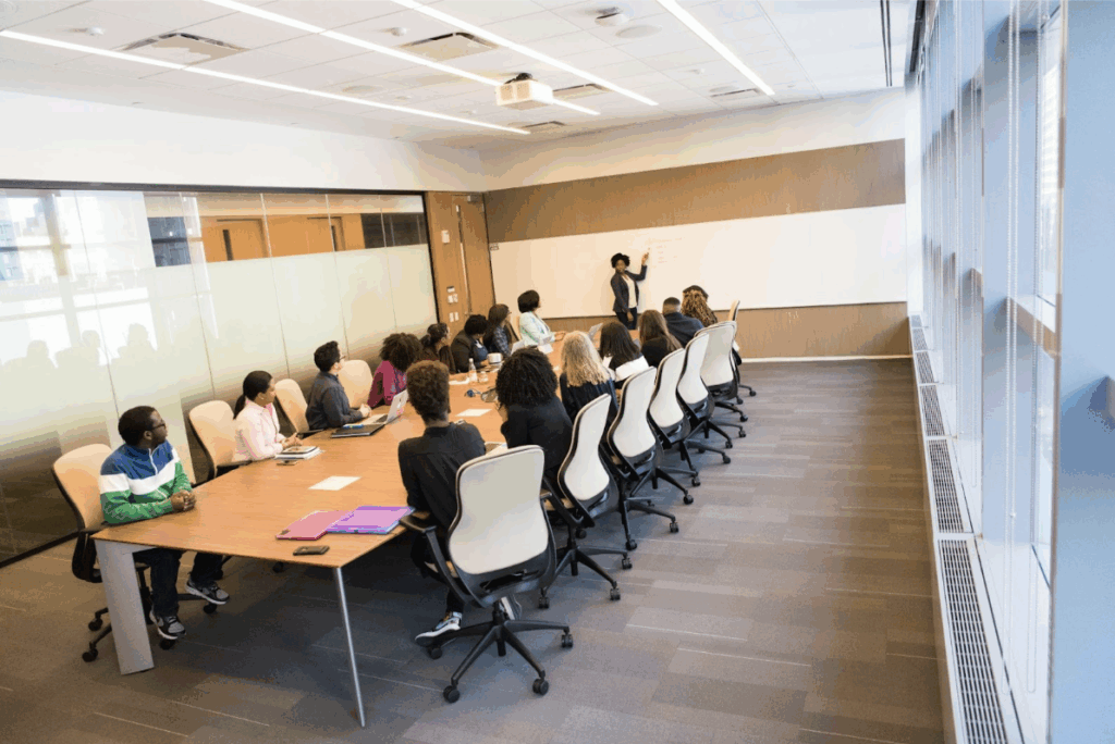 Facilitator: A group of people at a long table sitting in on a meeting