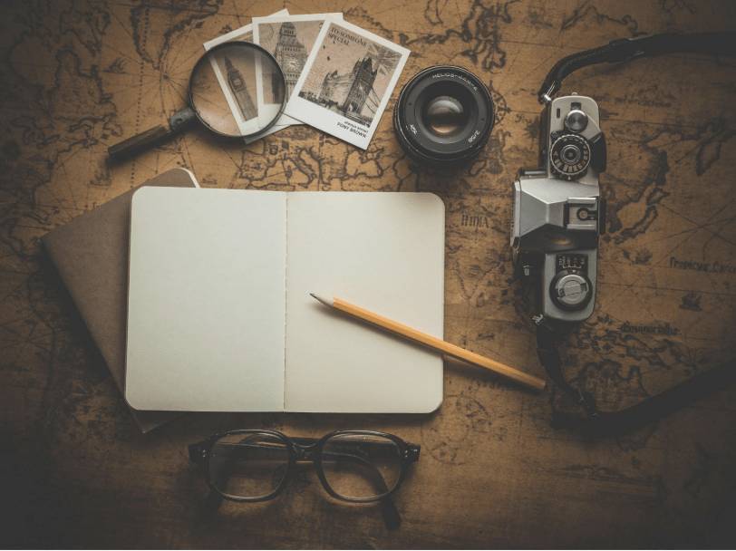 A New Framework for Conflict Resolution: Notebook open on a table with a camera and magnifying glass.